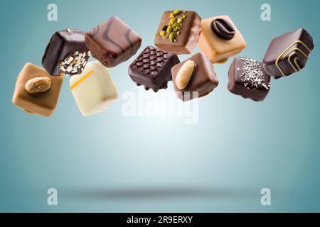 Assorted chocolate pralines floating on blue background Stock Photo