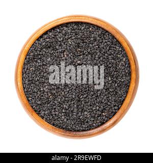 Black sesame, in a wooden bowl. Unhulled seeds of Sesamum indicum, with rich and nutty flavor, and with one of the highest oil content of any seed. Stock Photo