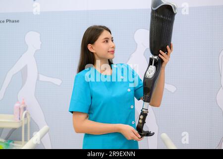 Female technician holding prosthetic limb checking in medical clinic Stock Photo
