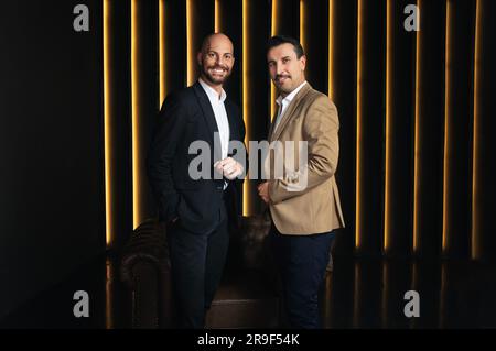Two Successful Businessmen Standing In Luxury Interior Of Dark Office Stock Photo
