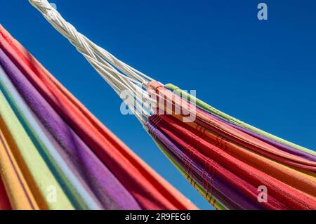 Close-up image of two rainbow-colored hammocks against the blue sky Stock Photo