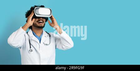 Indian doctor using wireless VR goggles, blue background Stock Photo