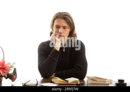 A young student sits at a table and thinks. Stock Photo
