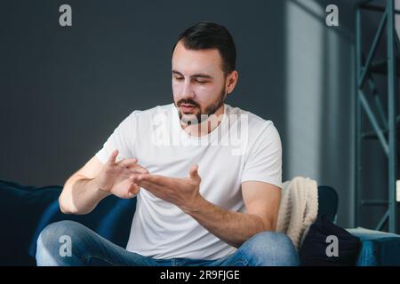 Cheerful young man sitting on floor and looking at camera Stock Photo