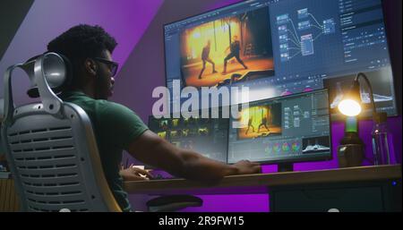 African American video editor makes color grading, works at home office. Computer and big digital screen with program interface with RGB tools and action movie footage. Film post production concept. Stock Photo