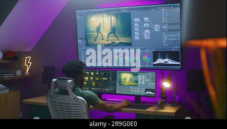 African American video maker edits action movie, makes color grading, works at home. Software interface with RGB tools and wheels on computer and big digital screen. Concept of film post production. Stock Photo