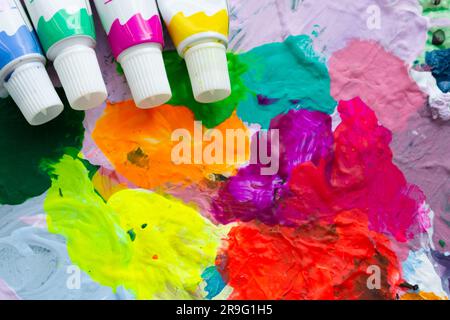 Background, multi-colored bright abstraction of various colors and four tubes of paints in the upper corner. Stock Photo