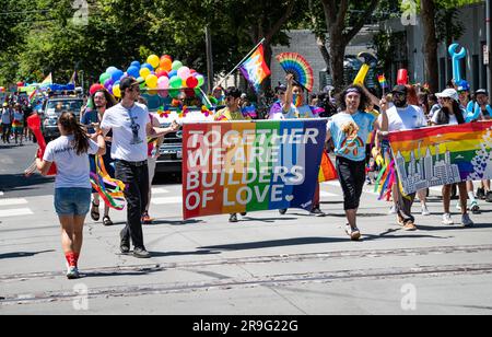 A group from the outdoor company REI holds a rainbow sign that says "Together we are builders of love" as part of the annual Pride parade event. Stock Photo