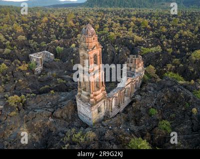 The ruins at Paricutin Volcano situated on a rocky landscape surrounded by lush greenery Stock Photo