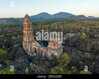 The ruins at Paricutin Volcano situated on a rocky landscape surrounded by lush greenery Stock Photo