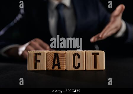 A man's hand shows the word fact on a wooden cube. truth concept Stock Photo