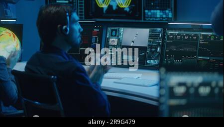 Diverse flight control operators in headsets monitor space mission on ...