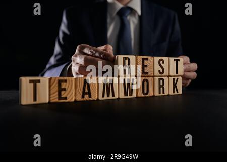 A businessman holds in his hands a wooden cube block with words on the background of the table Stock Photo
