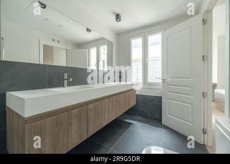 Photo of a beautiful contemporary bathroom with a long double sink and a wooden base unit with clean and straight lines in a minimalist style Stock Photo