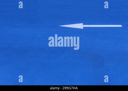 White painted indicator arrow on blue surface Stock Photo