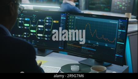 Multiracial team of IT software engineers work in monitoring office. Data server, blockchain network and live analysis charts displayed on computers and big digital screens. Concept of cyber security. Stock Photo