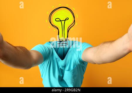 Man with drawn glowing light bulb instead of his head on orange background. Concept of new idea Stock Photo