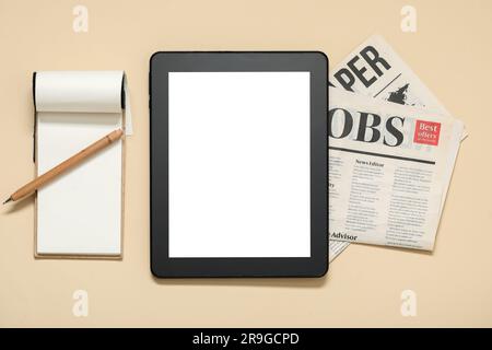 Modern tablet computer, notebook, pen and folded newspaper on beige background Stock Photo