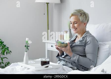 Mature woman having breakfast in bed Stock Photo