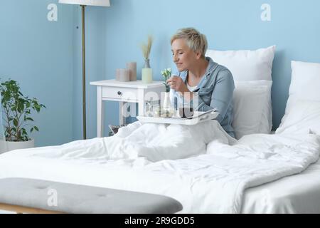 Mature woman having breakfast in bed Stock Photo