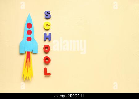 Paper rocket with word SCHOOL on beige background Stock Photo