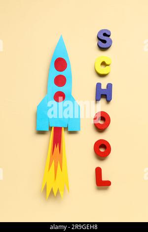 Paper rocket with word SCHOOL on beige background Stock Photo