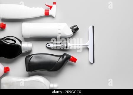 White plastic squeegee and bottles of detergent on grey background Stock Photo