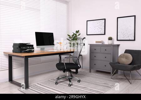 Stylish room interior with desk, modern printer and computer Stock Photo