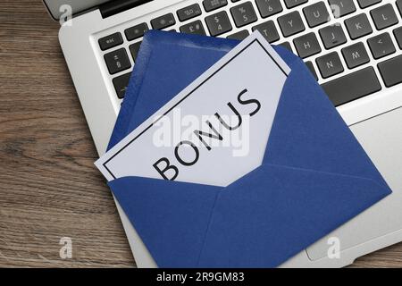 Blue envelope, letter with word Bonus and laptop on wooden table, top view Stock Photo