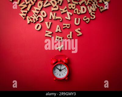 Top view red alarm clock and wooden word on a red background Stock Photo