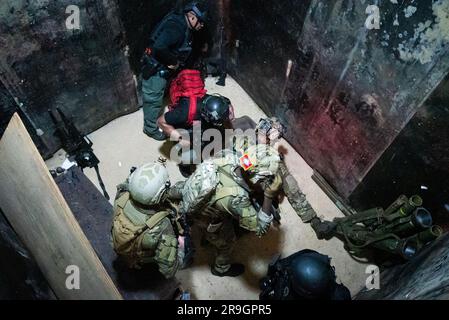 NAVAL BASE GUAM, Guam. (May 11, 2023) –Sailors from Explosive Ordnance Disposal Mobile Unit Five, assigned to Commander. Task Force (CTF) 75, EOD Marines assigned to the 9th Engineering Support Battalion and officers from the Guam Police Department conduct a raid drill and simulated casualty evacuation onto an MH-60S Sea Hawk helicopter assigned to the “Blackjacks” of Helicopter Sea Combat Squadron Two-One (HSC) 21 during a field training training exercise near Naval Base Guam. This training exercise strengthens readiness in inserting personnel into a military area of operations. CTF 75 execut Stock Photo