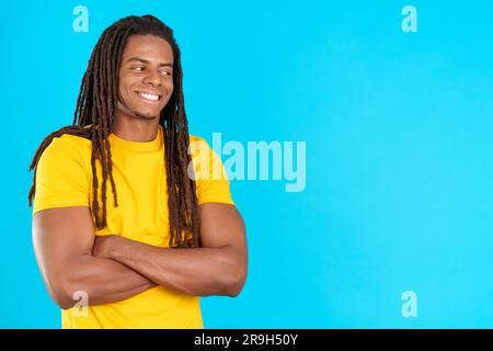 Happy latin man with dreadlocks standing looking away while smiling Stock Photo