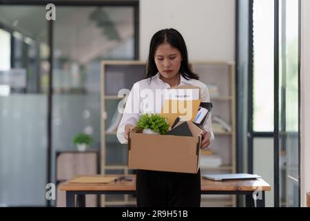 Resignation concept. Fired employee holding box of belongings in an office Stock Photo