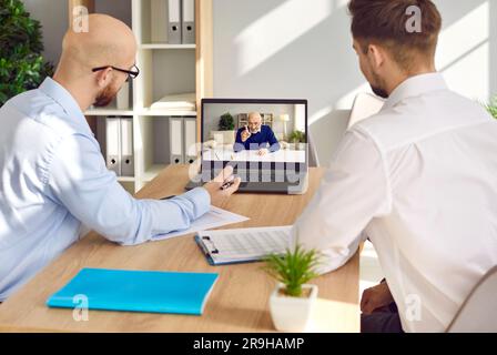 Young business employees using laptop computer and having online meeting with boss Stock Photo