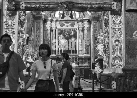 black and white blurred couple of asian tourists come out of Chapel of the Langue of Aragon inside St. John's Co-Cathedral in Valletta, Malta Stock Photo