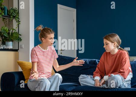 Excited mother spread arms while talk to teen daughter, ignoring misunderstanding of transition age Stock Photo