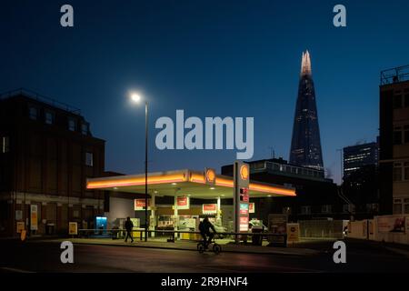 The Shard skyscraper building beyond an illuminated Shell Plc petrol station at dawn in London, UK Stock Photo