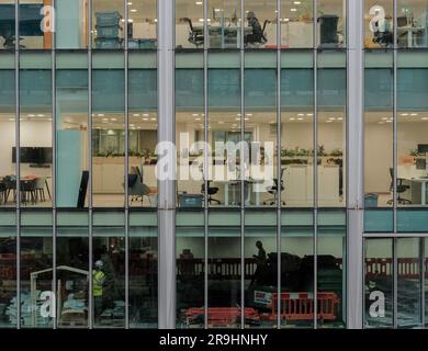 Construction workers on a building site on the level below workers in an office building in the city of London financial district, London, England Stock Photo