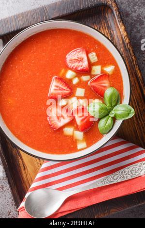 Spanish Tomato Strawberry Gazpacho cold soup on a wooden board close-up on the table. Vertical top view from above Stock Photo