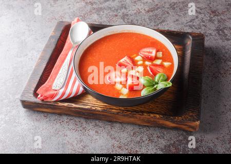 Cold summer tomato soup gazpacho with strawberries, cucumbers and basil close-up in a bowl on the table. Horizontal Stock Photo