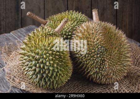 Durian fruit cut in half on a wooden table. The durian is the edible fruit of several tree species belonging to the genus Durio. Stock Photo