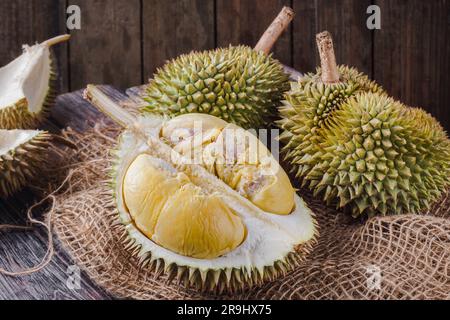 Durian fruit cut in half on a wooden table. The durian is the edible fruit of several tree species belonging to the genus Durio. Stock Photo