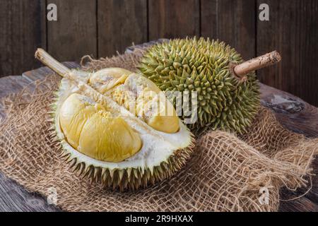 Durian fruit cut in half on a wooden table. The durian is the edible fruit of several tree species belonging to the genus Durio. Stock Photo