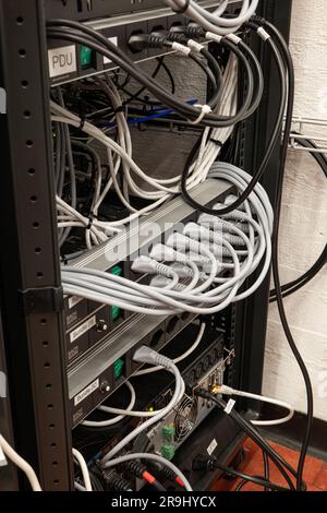 Neatly organized power cord extension cables with fully used plugs on an industrial rack. Indoors, no people. Stock Photo