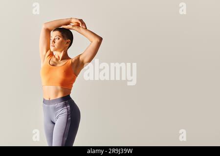 body confidence, athletic and short haired woman posing on grey background, curvy  fitness model, standing with raised hand, endurance and empowerment Stock  Photo - Alamy