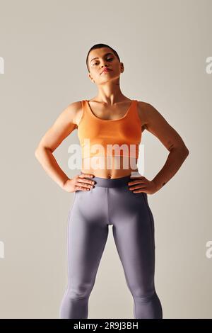 body confidence, athletic and short haired woman posing on grey background, curvy  fitness model, standing with raised hand, endurance and empowerment Stock  Photo - Alamy