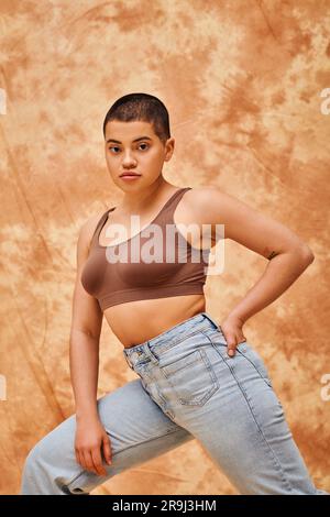 Curvy woman with hand in pocket standing in front of wall Stock