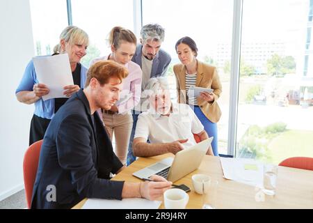 Colleagues discussing over laptop while planning strategy at office Stock Photo
