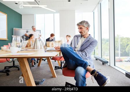 Businessman using laptop sitting at table in conference room Stock Photo