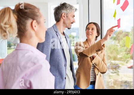 Businessman discussing over sticky notes with female colleagues Stock Photo
